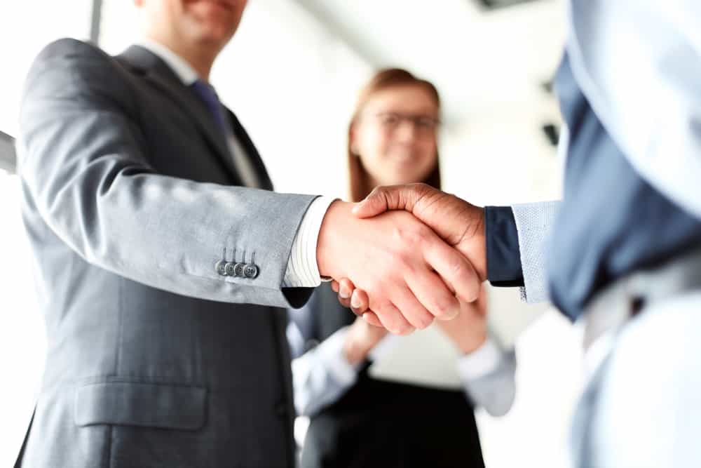 two private equity investors shake hands becuase they increased portfolio value